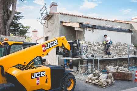 NOIRMOUTIER, FRANCE - june 16, 2017: mason renovates a house with stone in the tradition of...