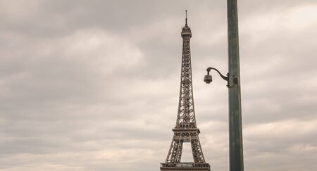 black security camera on a pillar in bad weather in front of the Eiffel Tower