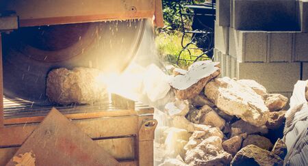 Man cutting a stone with a water saw on a renovation siteの写真素材