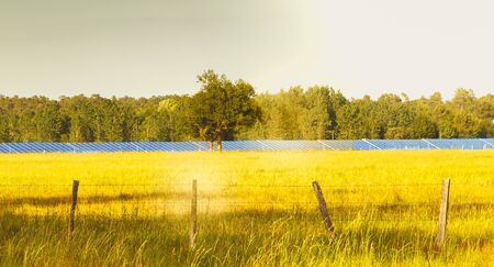 behind a meadow a large field of solar panels in Franceの写真素材