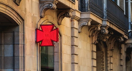 Barcelona, Spain - June 20, 2017 : red cross of a catalonia pharmacy on a summer dayのeditorial素材