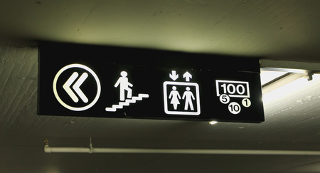 illuminated signs that indicates the direction of the stairs elevator and cash machine in a basement in switzerlandの写真素材
