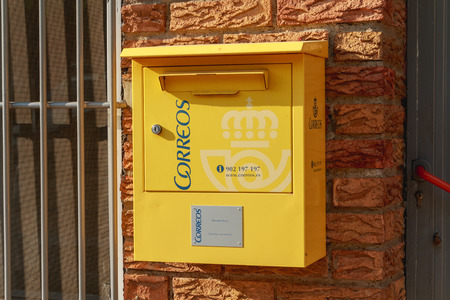 Huesca, Spain - June 21, 2017 : yellow mailbox of the Spanish postal distribution company Correos on a wall in summerのeditorial素材