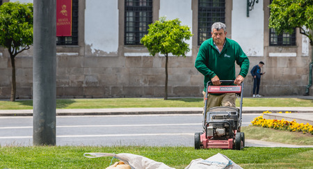 Braga, Portugal - May 23, 2018: Municipal gardeners mowing the grass in the city center on a spring...