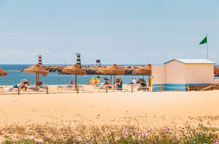 Vilamoura, Portugal - May 1, 2018: Traditional seaside algarve parasol under which people sit looking at the sea on a spring dayのeditorial素材