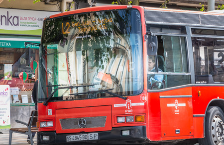 Irun, Spain - April 27, 2018: Public bus stopped at a station near a sidewalk where people walk a spring dayのeditorial素材