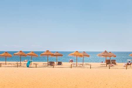 Vilamoura, Portugal - May 1, 2018: Traditional seaside algarve parasol under which people sit looking at the sea on a spring dayのeditorial素材