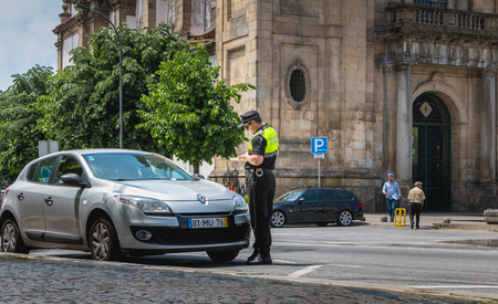 Braga, Portugal - May 23, 2018: policeman checks and writes a traffic ticket on a car in the city center on a spring dayのeditorial素材