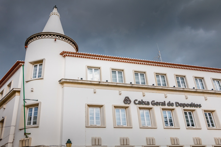 Faro, Portugal - May 1, 2018: facade of an agency of the Portuguese bank Caixa Geral de Depositos in front of which passers-by walk on a spring day.のeditorial素材