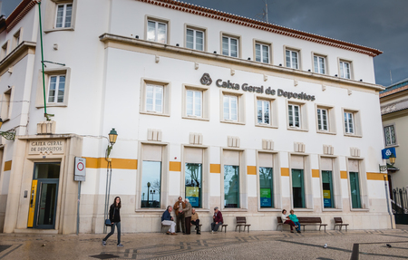 Faro, Portugal - May 1, 2018: facade of an agency of the Portuguese bank Caixa Geral de Depositos in front of which passers-by walk on a spring day.のeditorial素材