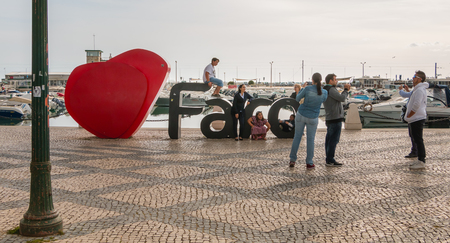 Faro, Portugal - May 1, 2018: Faro city logo name with big letters near the marina in front of which tourists take pictures on a spring dayのeditorial素材