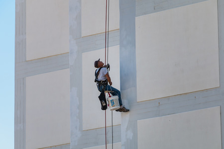 Sesimbra, Portugal - August 8, 2018: painter coming down the facade of a building rappelling with a ropeのeditorial素材