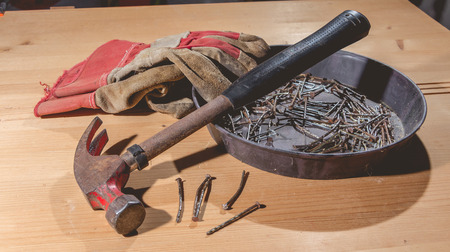 old rusty hammer and construction gloves laid on wooden board in studio