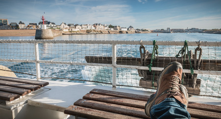 relaxed man sitting at the back of a ferry leaving the port towards Yeu Islandの写真素材