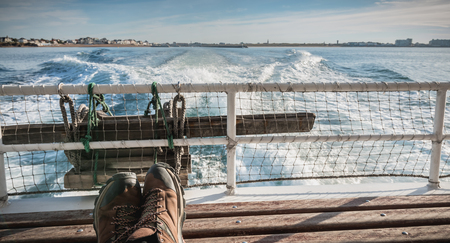 relaxed man sitting at the back of a ferry leaving the port towards Yeu Islandの写真素材