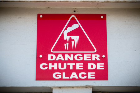 red sign in the mountains where it is written in French - danger ice fallの写真素材