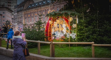 Strasbourg, France - December 28, 2017: mature woman taking a picture of the Christmas market logo. It is written in French Strasbourg capital of Christmasのeditorial素材