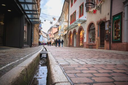 Freiburg im Breisgau, Germany - December 31, 2017: People walking on a small cobblestone street with typical architecture houses in the historic city center on a winter dayのeditorial素材