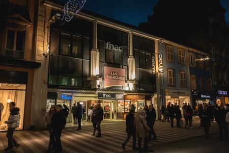Belfort, France - December 26, 2017: pedestrians dressed warmly strolling in a night shopping street decorated for the holiday season.のeditorial素材