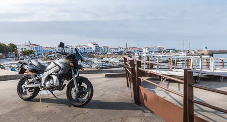 Yeu island, France - September 18, 2018: Motorcycle parked in harbor port Joinville near boats on a summer dayのeditorial素材