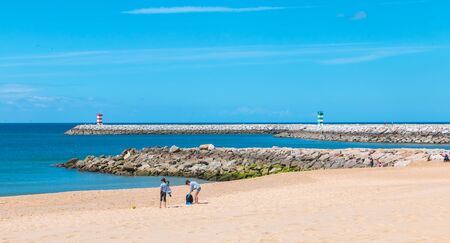 Quarteira, Portugal - May 1, 2018: People walking by the sea on a spring dayのeditorial素材