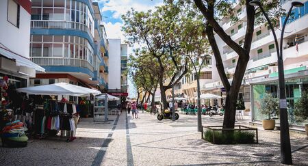 Quarteira, Portugal - May 1, 2018: Downtown shopping street atmosphere where people are walking on a spring dayのeditorial素材
