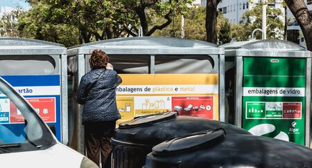 Quarteira, Portugal - May 1, 2018: Lady throwing trash into a public garbage bin for plastic and...