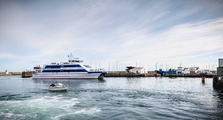 Ile d Yeu, France - September 16, 2018: ferry that enters the harbor of the island of Yeu where travelers are sitting to admire the show on a summer dayのeditorial素材
