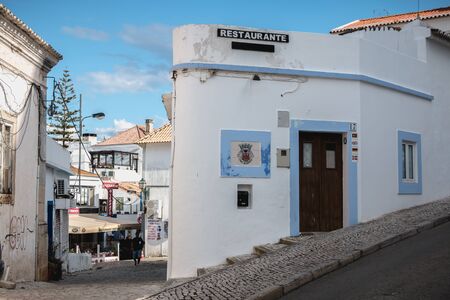 Albufeira, Portugal - May 3, 2018: Street atmosphere and souvenir shop architecture and restaurants in a busy downtown shopping street where tourists walk on a spring dayのeditorial素材