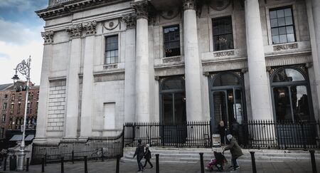 Dublin, Ireland - February 16, 2019: Tourists walking outside the exterior of Dublin City Hall which...