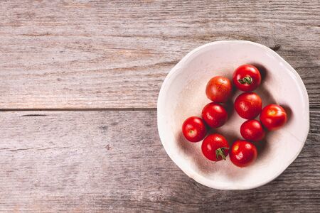 Plate of ripe tomatoes on wooden board background in studioの写真素材