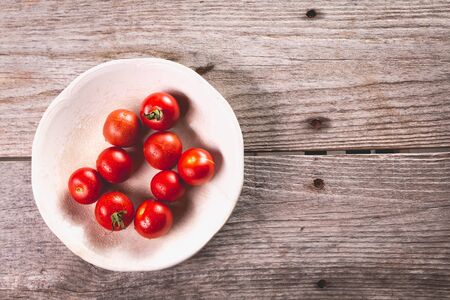 Plate of ripe tomatoes on wooden board background in studioの写真素材