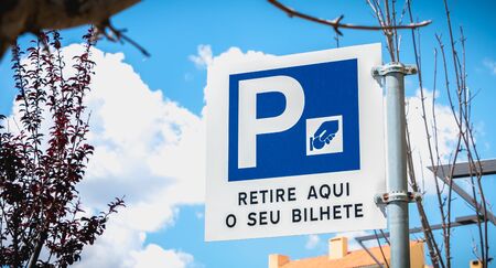 road sign indicating an automatic parking payment machine where it is written in Portuguese collect your ticket here (retire aqui o seu bilhete)の写真素材