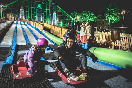 Belfort, France - December 26, 2017: children and adults tobogganing on an ice slide installed at the Christmas party in the city centerのeditorial素材