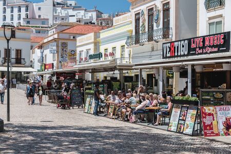 Albufeira, Portugal - May 4, 2018: Street ambiance and architecture on the terraces of cafes and restaurants in the tourist town center where people consume and relax on a spring dayのeditorial素材