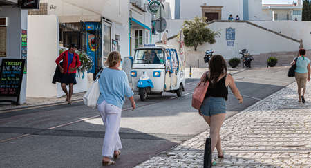Albufeira, Portugal - May 3, 2018: Tuk Tuk carrying tourists traveling on a street in the historic...