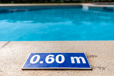 Blue plastic plate at the edge of a swimming pool indicating a depth of 0.60 meters