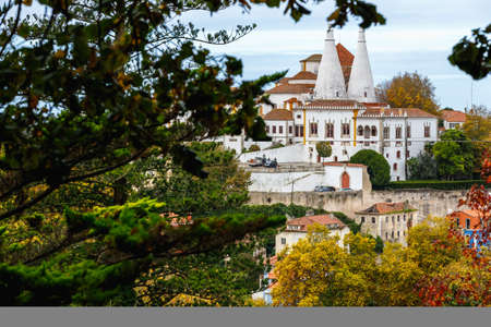 Sintra, Portugal - October 28, 2020: Architectural detail of the National Palace of Sintra, also called the Royal Palace with its 2 chimneys of 33 meters behind trees on a winter dayのeditorial素材