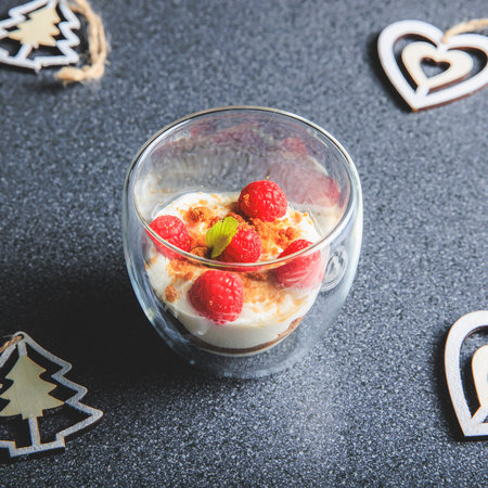 Verrine of crushed speculoos, mascarpone and raspberries on a gray background decorated for Christmas in the studioの写真素材