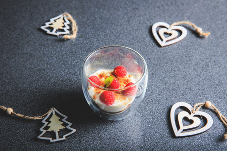 Verrine of crushed speculoos, mascarpone and raspberries on a gray background decorated for Christmas in the studioの写真素材