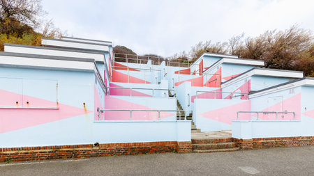 Folkestone, UK - December 30, 2024: Typical colorful beach huts by the sea on a gray winter dayのeditorial素材