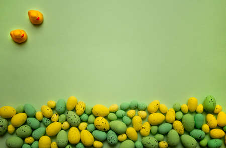Yellow and green Easter eggs on green background with yellow ducks. Spring holidays concept