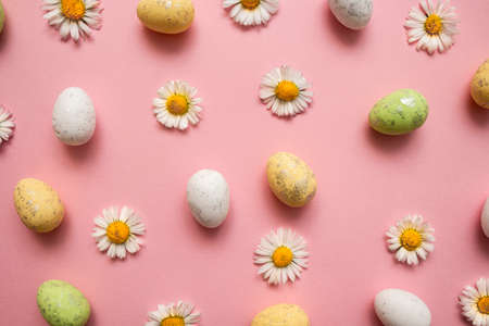 Colorful Easter eggs and flowers on pink background. Spring holidays concept