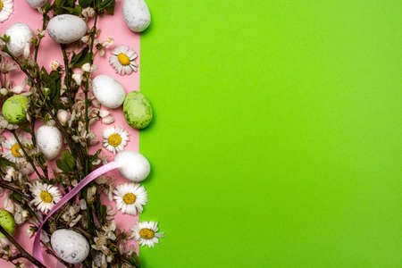 Colorful Easter eggs and flowers on pink and green background. Spring holidays conceptの写真素材