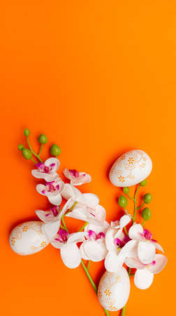 White Easter eggs and flowers on orange background. Spring holidays conceptの写真素材