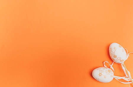 White Easter eggs on orange background. Spring holidays concept