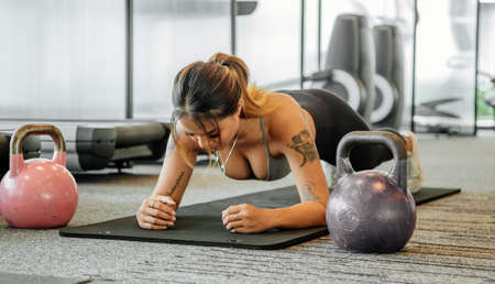 Asian sports woman in the gym, athletes training, workout lifting weight, plank and push up. tattoo thai girlの写真素材