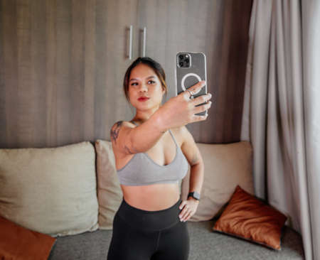 Young Asian healthy woman workout at home, exercise looking at videos, fit, doing yoga, plank, abs, meditation. Bodyweight floor exercises. Healthy lifestyle. Home fitness conceptの写真素材