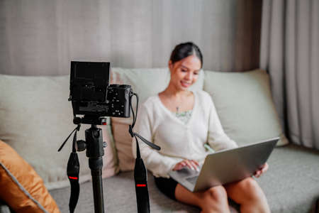 Asian blogger, podcaster or vlogger looking at camera and talking on video shooting with technology. Social media influencer people or content maker concept in relax casual style at homeの写真素材