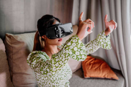 Asian Woman looking through virtual reality device at home. Augmented reality, game, future technology concept.VRの写真素材